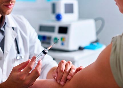 Врач вводит инъекцию в руку пациента в медицинском кабинете